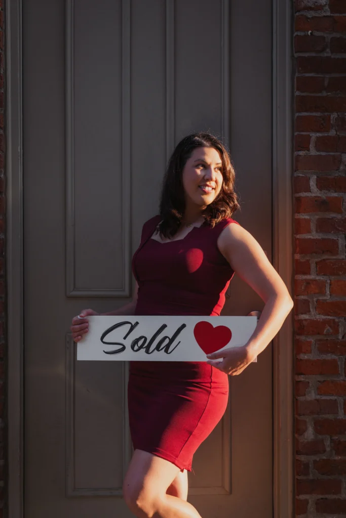realtor posing with a sold sign outside a house in the Over-the-Rhine neighborhood