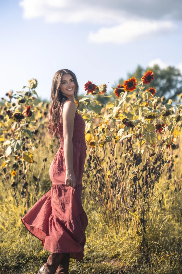 senior smiling at the camera during photoshoot in sun flowers at Clover farm near Batavia Ohio and Cincinnati